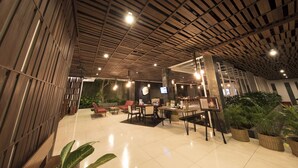 A spacious lobby with a high ceiling, modern furniture, and potted plants.