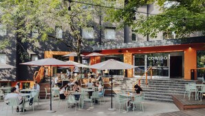 An outdoor café with tables and chairs, a staircase leading to a building entrance, and a sign reading "COMBO". - Combo Bologna - Hostel (Bologna)