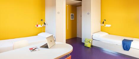 A room with two beds, a desk, and a chair.