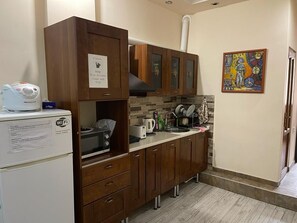 A compact kitchen with wooden cabinets, a microwave, a toaster, and a sink. - Yerevan Hostel (Yerevan)