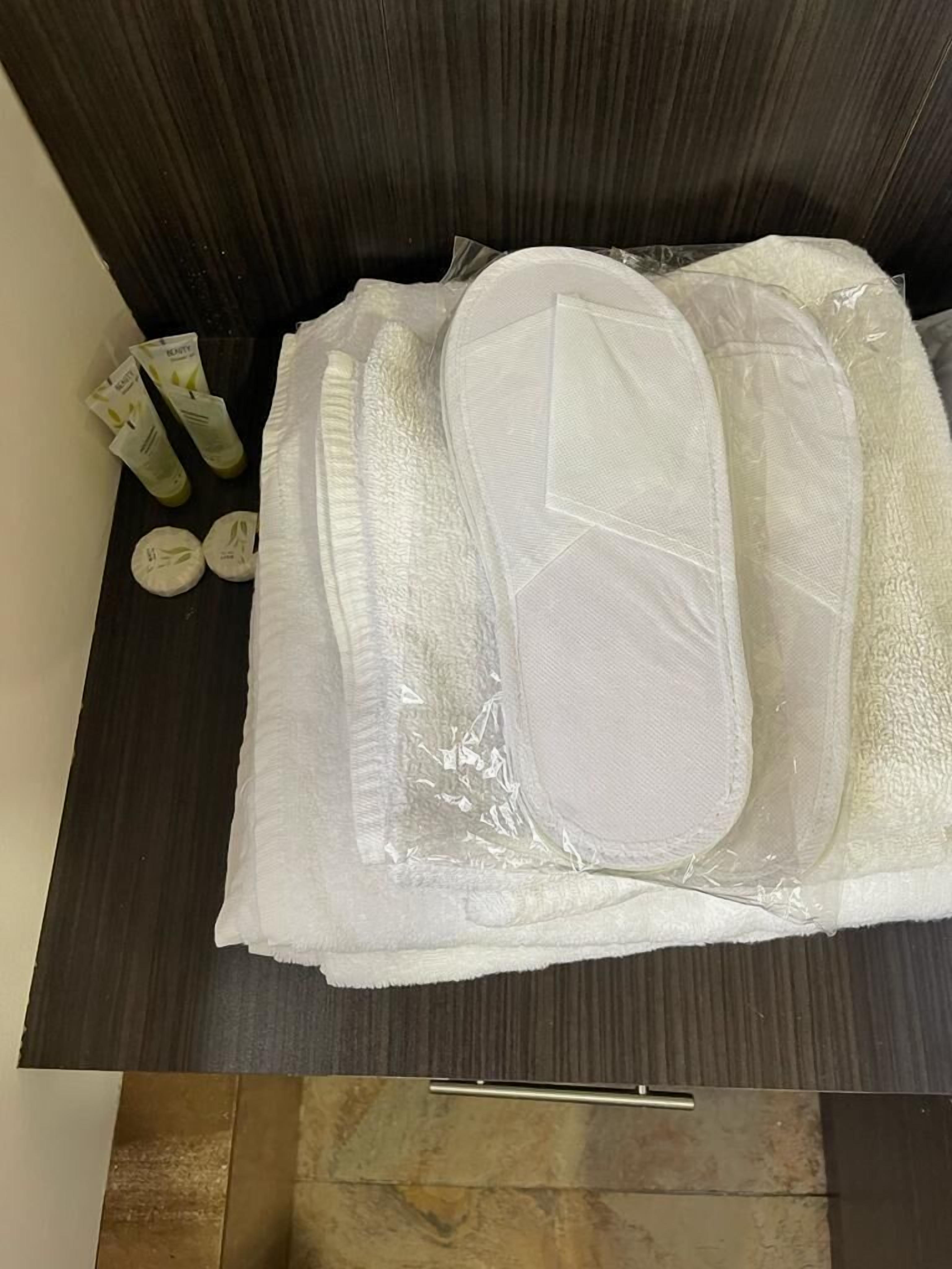 A bathroom with a dark wood vanity, a white towel, and toiletries including a bottle and a tube.
