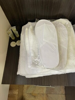 A bathroom with a dark wood vanity, a white towel, and toiletries including a bottle and a tube. - Yerevan Hostel (Yerevan)