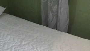 A neatly made bed with a textured white bedspread and two folded white towels on it. - Casa Nostra Hospedagem Residencial (Cabo Frio)