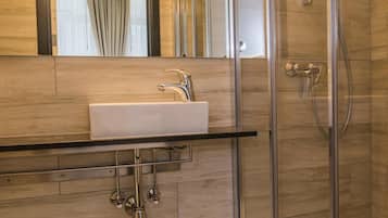 Une salle de bain moderne avec une douche à parois de verre, un lavabo blanc et un miroir au-dessus.