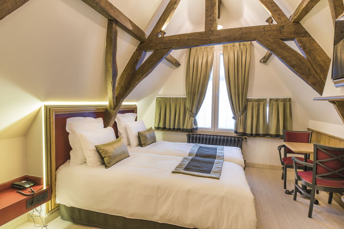 Un dormitorio con una cama grande, vigas de madera, un escritorio y sillas.