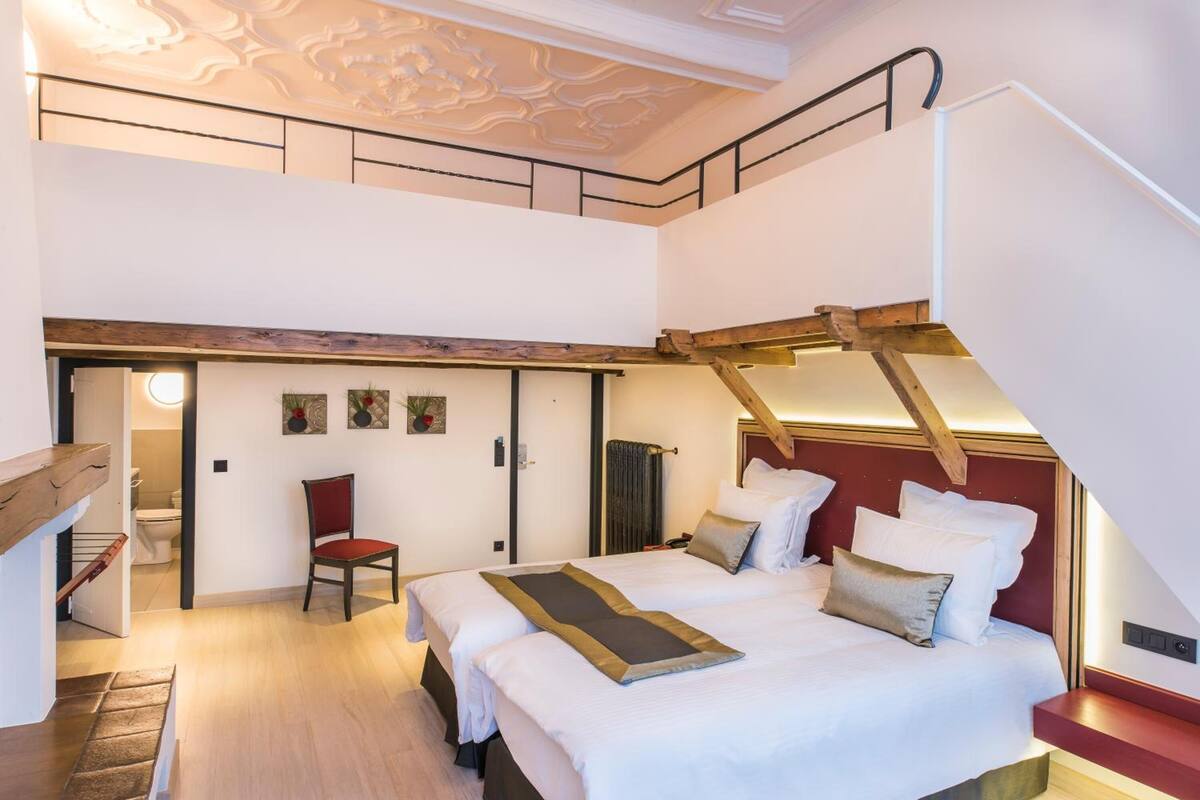 Un dormitorio con una cama grande, una silla y una escalera.