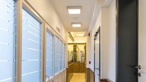 Un pasillo de hotel con suelo de madera, ventanas con vidrio esmerilado y una puerta negra a la derecha.