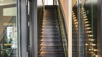 Entrada d'un hotel modern amb una porta de vidre, una escala que mena al pis superior i un felpú amb el nom de l'hotel.