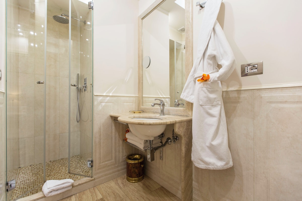 Un baño con ducha de vidrio, lavamanos y espejo.