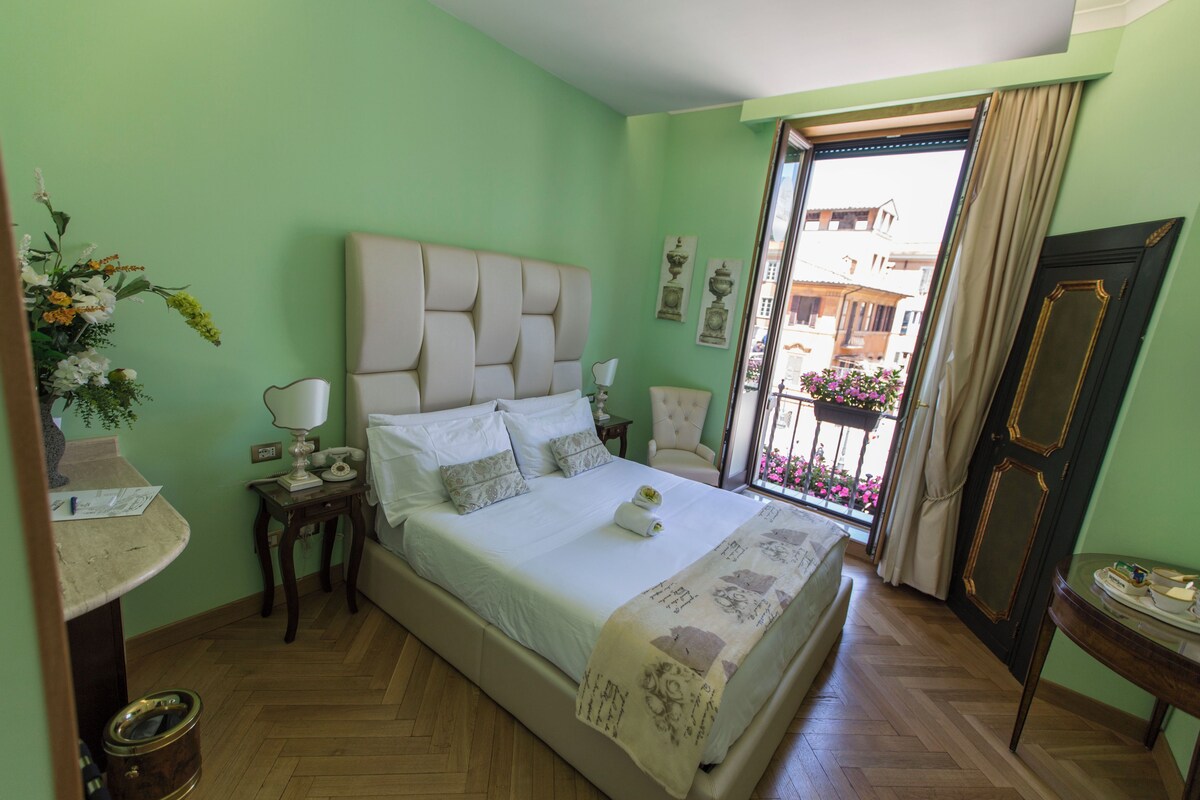 A neatly arranged bedroom with a large bed, a bedside table, and a chair.