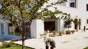 A modern building with a spacious patio area, potted plants, and a well-maintained lawn.