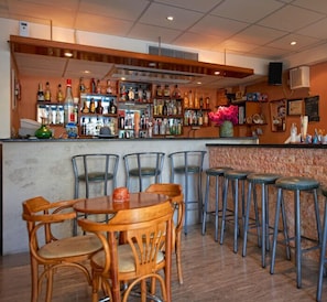 Eine Bar mit Holzhockern und -stühlen, einer Theke mit verschiedenen Flaschen und einer dekorativen Vase.