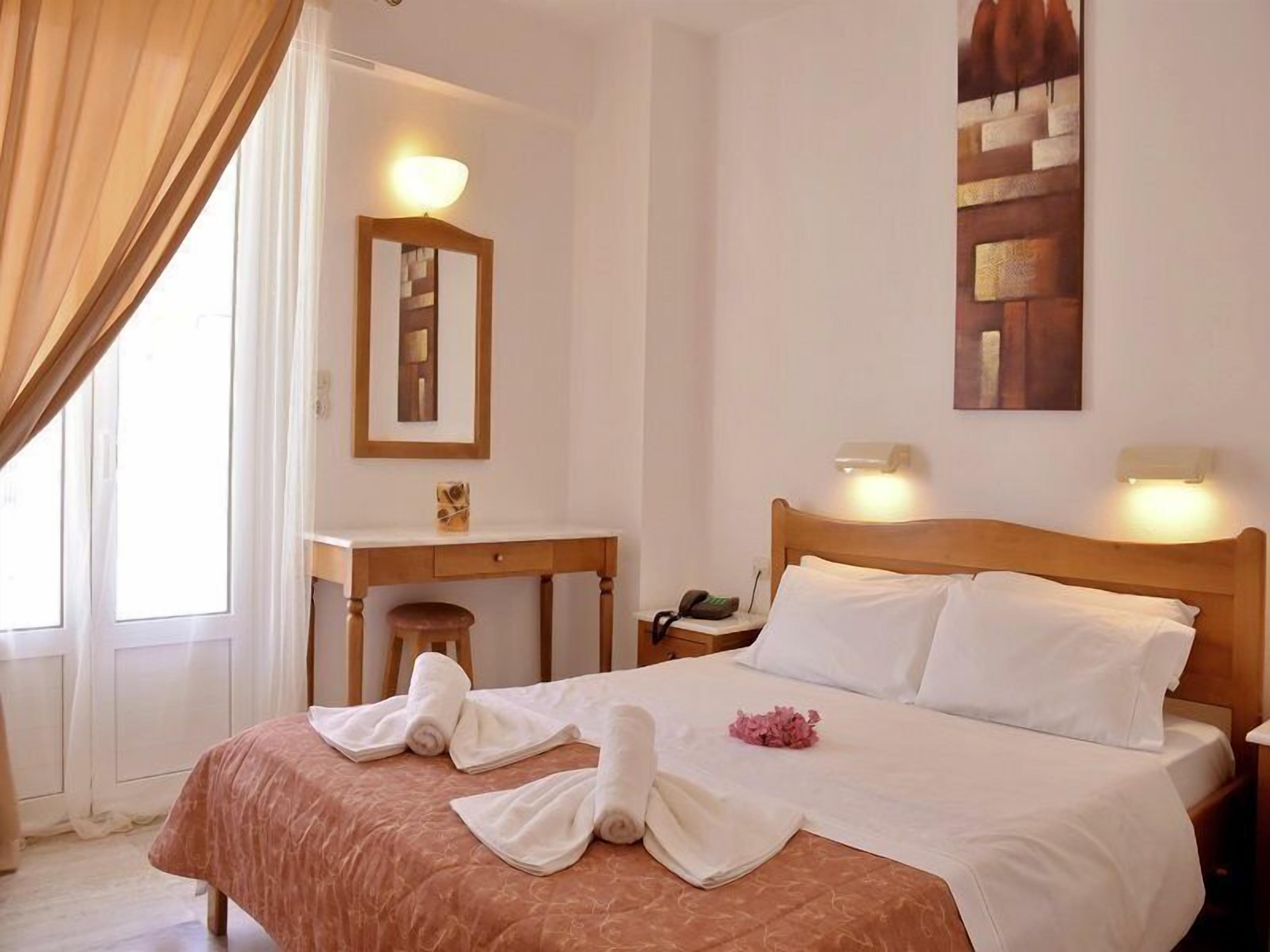 Una habitación de hotel con cama, escritorio, silla y espejo.
