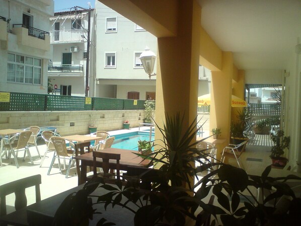 A poolside area with outdoor seating and potted plants. - Irini Apartments (Hersonissos)