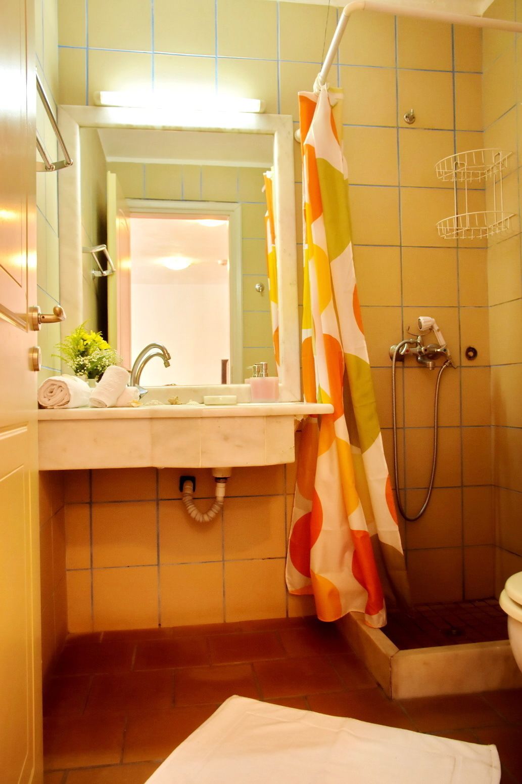 Un baño con lavamanos, espejo, ducha e inodoro.