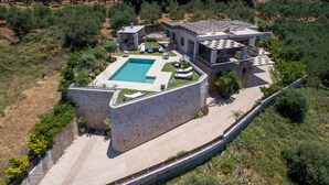 En vy från ovan av en modern villa med en swimmingpool, en uteplats och en stenmur.