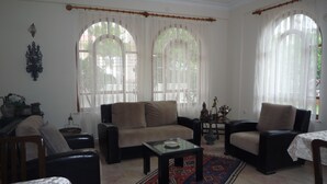 A living room with a sofa, armchairs, a coffee table, and a patterned rug. - Pinus Otel (Antalya)