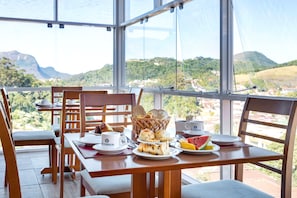 A dining table with breakfast items and a view of the landscape. - Hotel Petropolis Inn (Petrópolis)