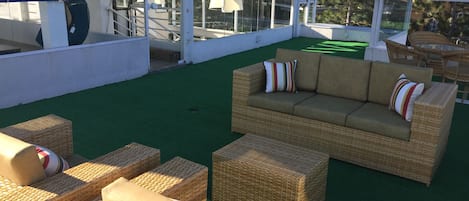 An outdoor seating area with wicker furniture and a green artificial turf.