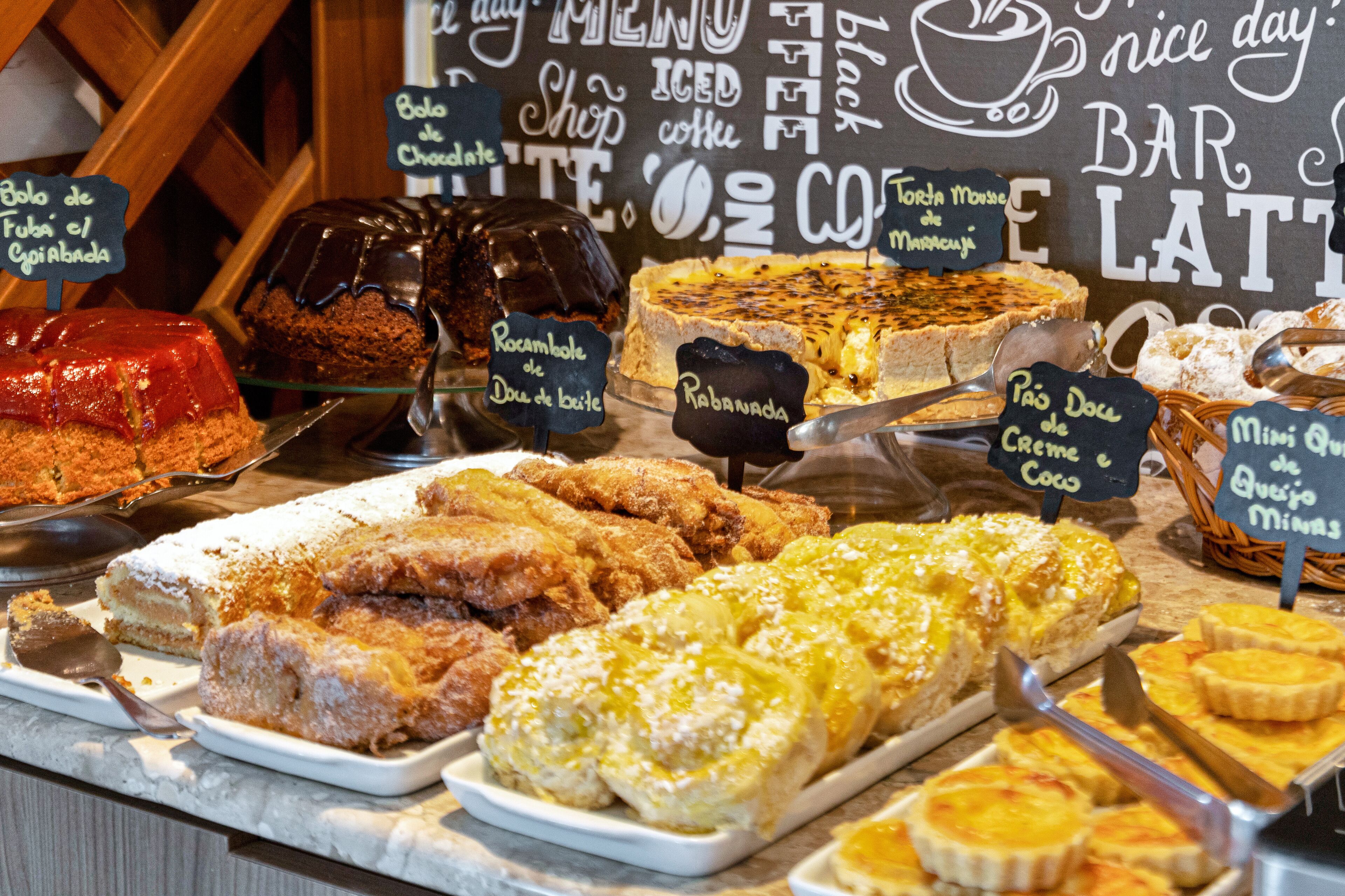 Diversos doces expostos em um balcão, em um ambiente de café.