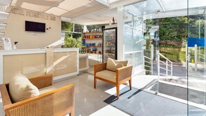 Un moderno vestíbulo de hotel con un mostrador de recepción, zona de estar y una pared de vidrio con vistas al exterior.