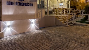 Un hotel moderno con fachada de vidrio, una escalera visible y un letrero que dice "HOTEL PETROPOLIS INN".