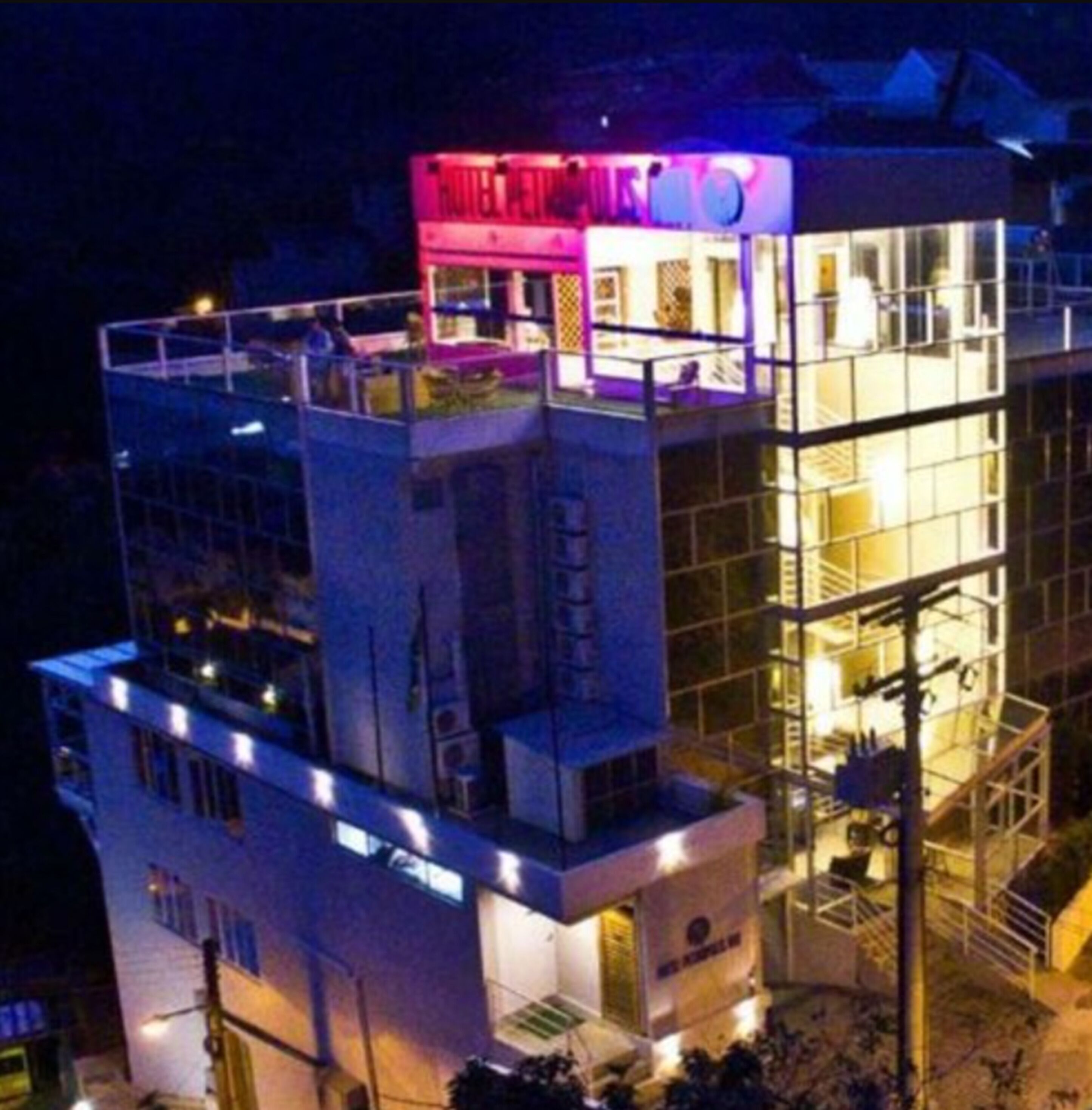A multi-story hotel with a rooftop terrace and a glass facade.