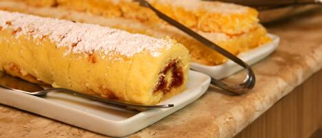 Una exhibición de postres con una variedad de pasteles sobre platos blancos, dispuestos sobre una encimera de mármol.
