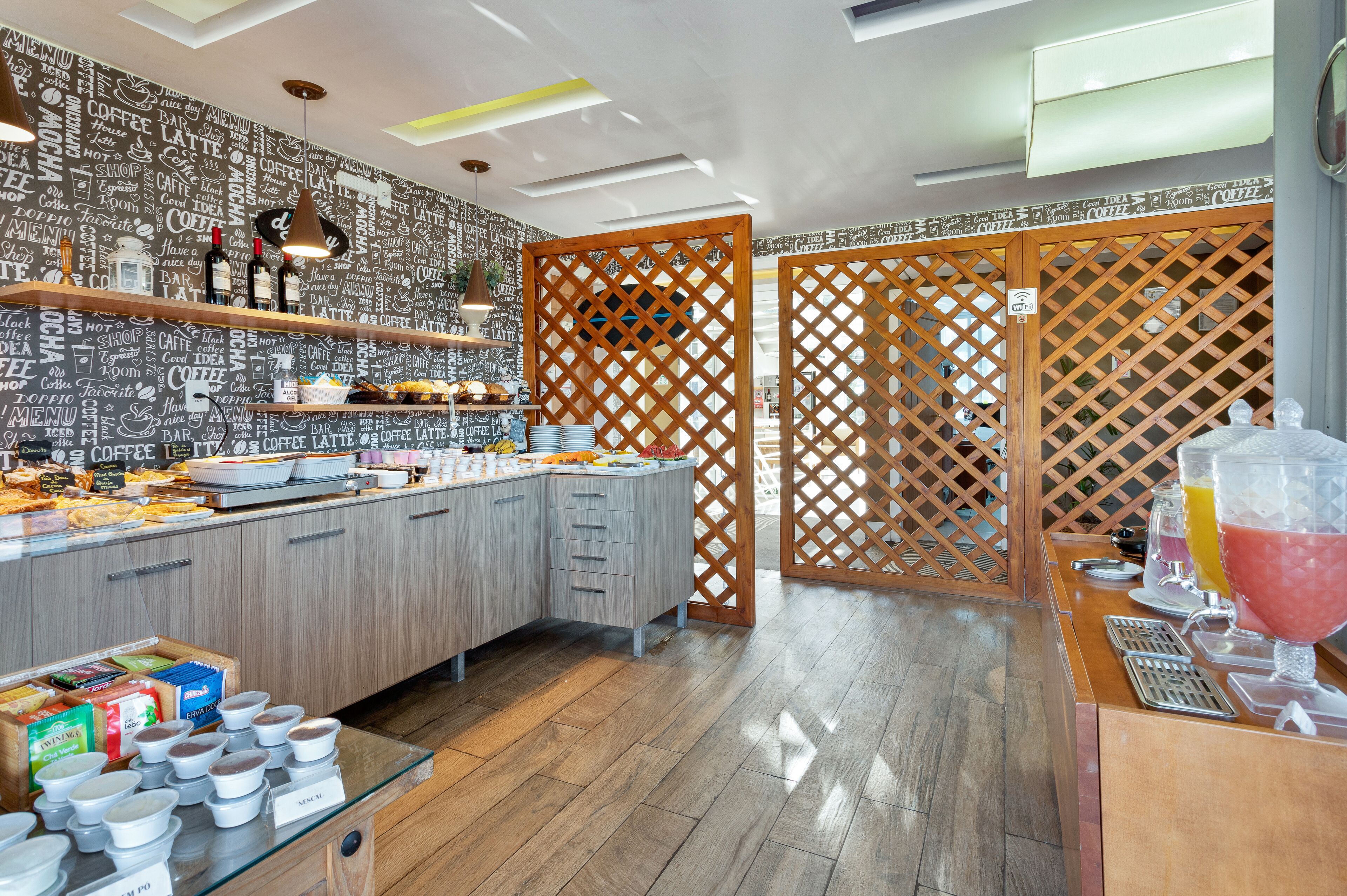 A modern cafe with a coffee-themed wall, wooden partitions, and a variety of food and drink options.
