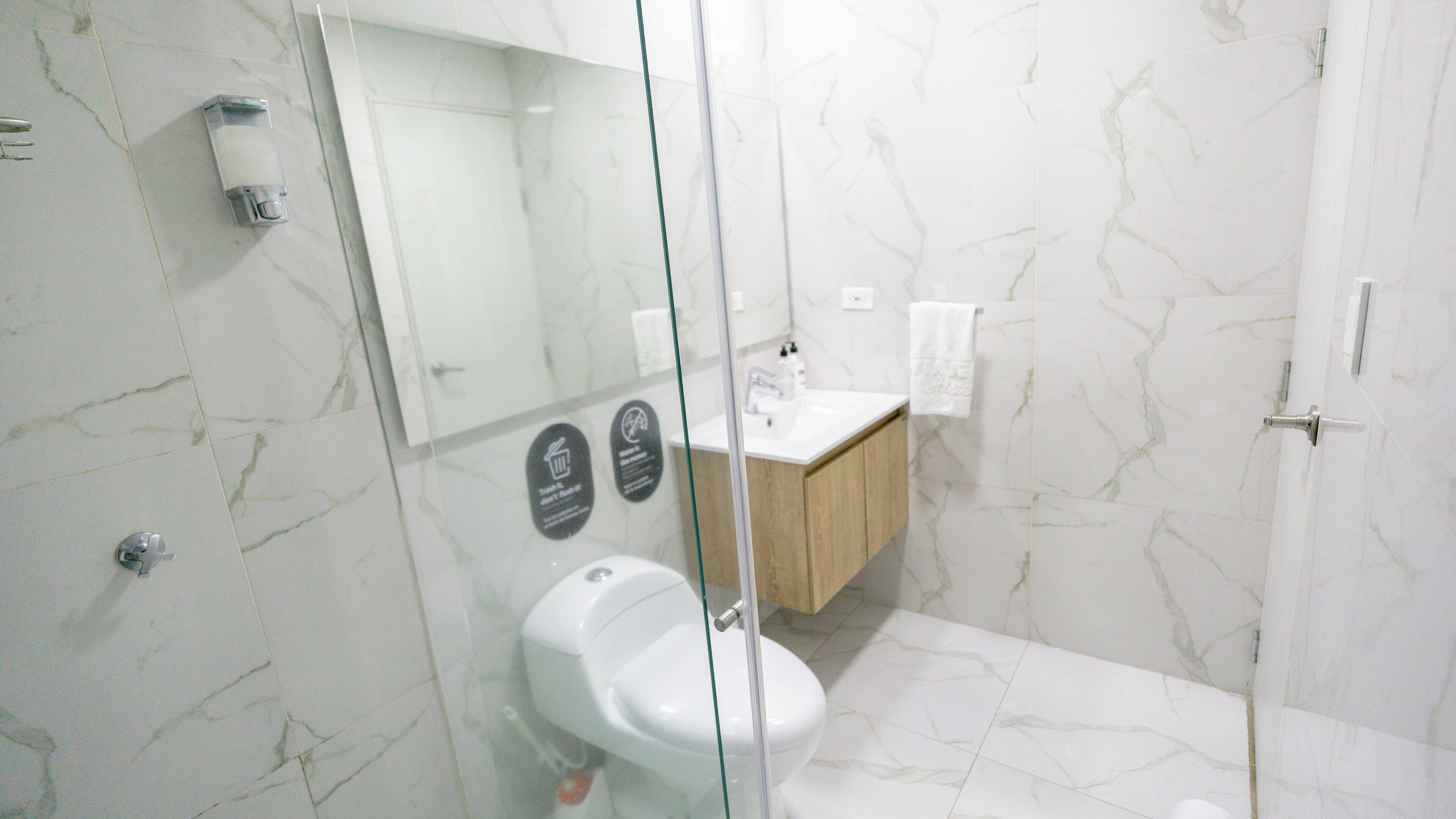 Een badkamer met een douchecabine van glas, een wastafel en een toilet.