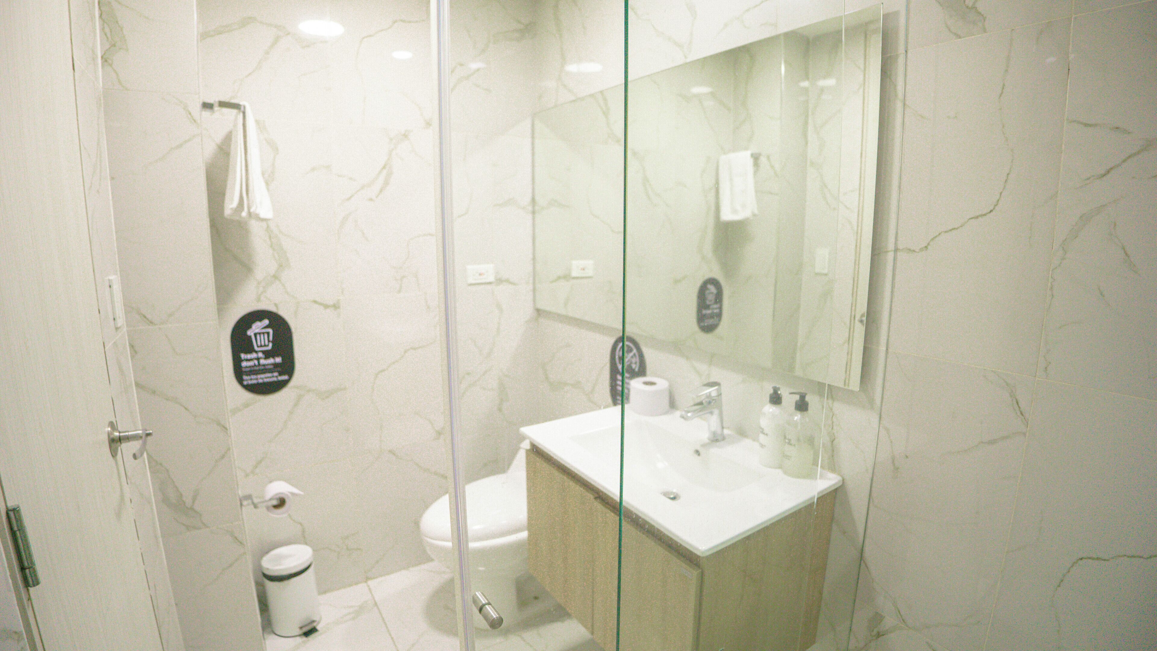 Une salle de bain moderne avec une douche à parois de verre, un lavabo blanc et des toilettes.