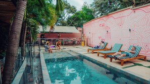 Una piscina al aire libre, sombrillas, sillones reclinables de piscina