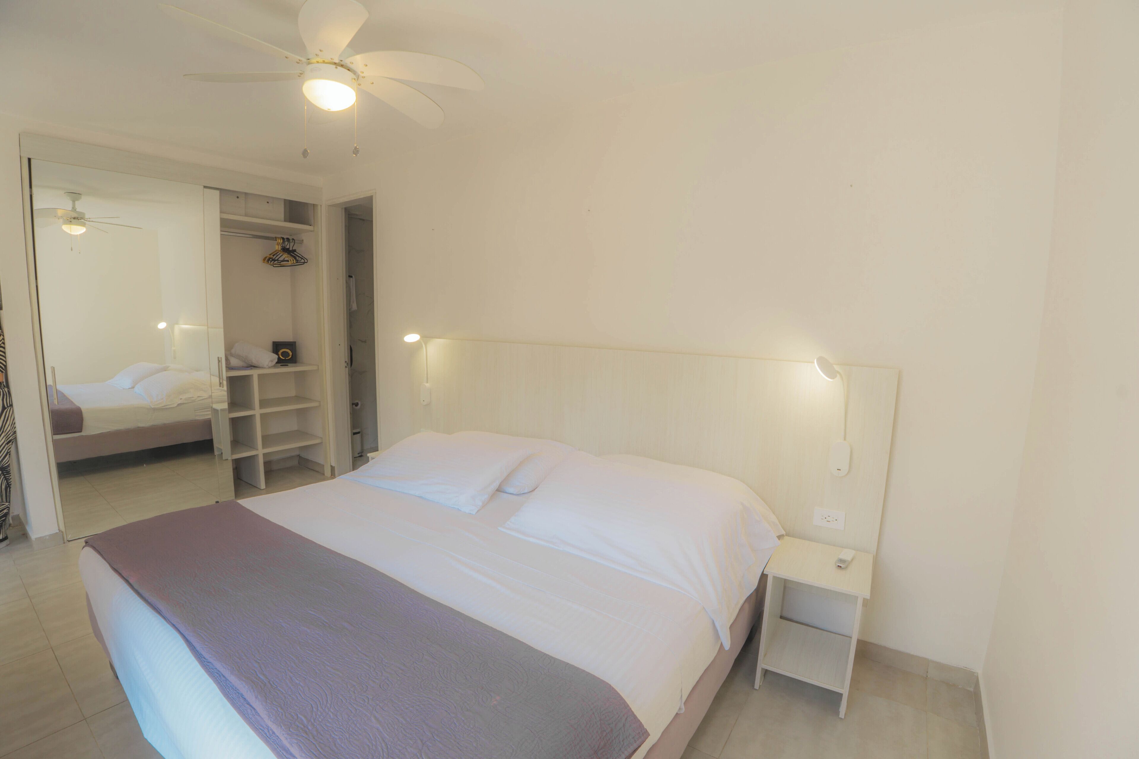 A bedroom with a bed, nightstand, and a walk-in closet.