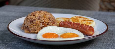 A plate with fried rice, two eggs, and a sausage.