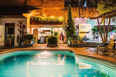Una piscina al aire libre, sombrillas, sillones reclinables de piscina