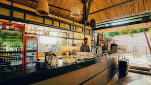 A bar with a counter, shelves with bottles, and a Coca-Cola cooler. - Viajero Cali Hostel & Salsa School (Cali)
