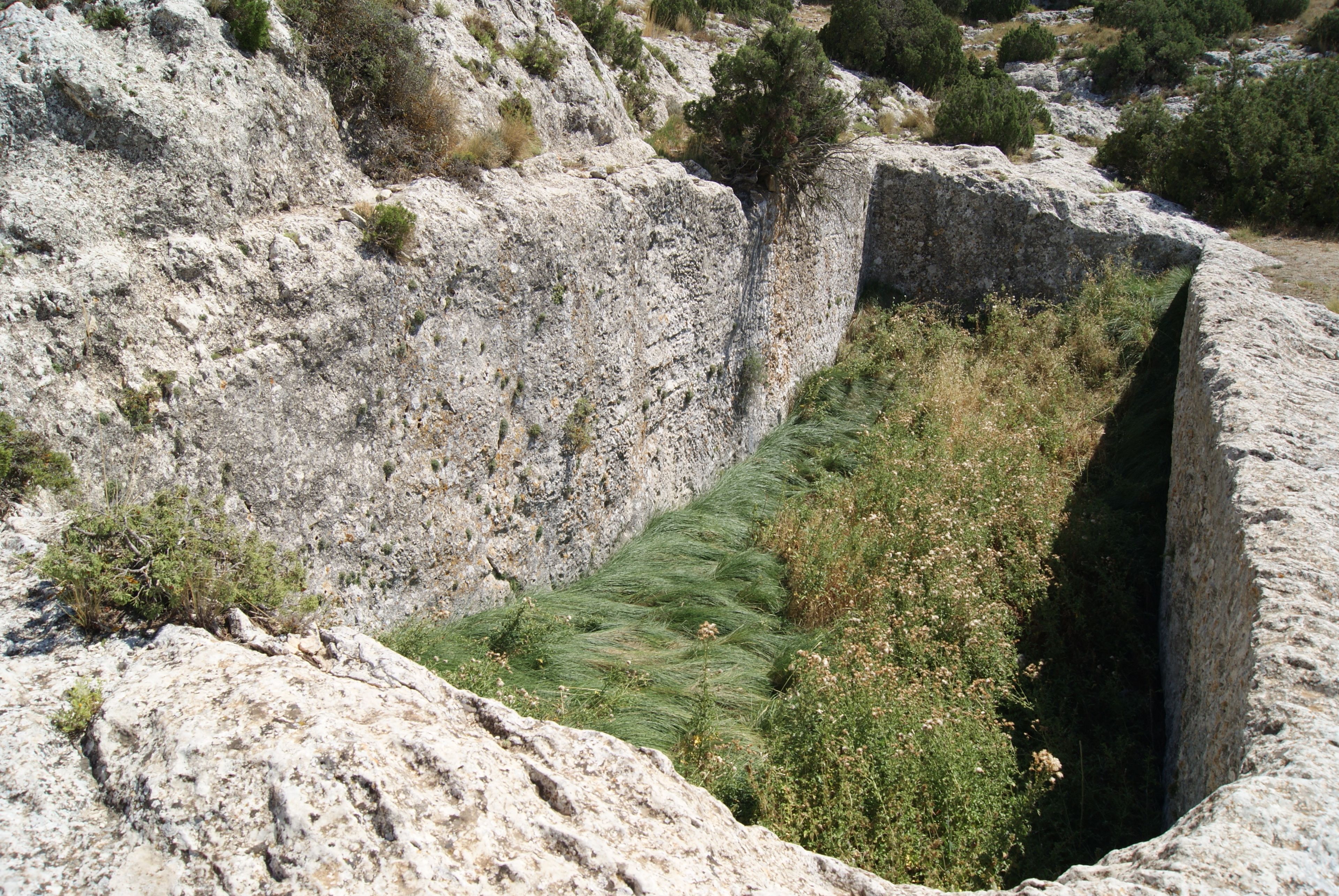 Un paysage rocheux, traversé d’une étroite tranchée artificielle.