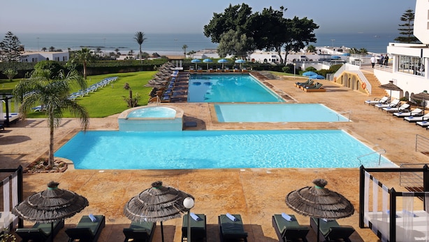 A pool area with multiple pools, lounge chairs, and umbrellas. - Anezi Apartments (Agadir)