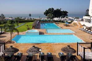 A pool area with multiple pools, lounge chairs, and umbrellas. - Anezi Apartments (Agadir)