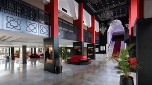 A spacious lobby with a high ceiling, red and black decor, and a staircase leading to an upper level. - Anezi Apartments (Agadir)
