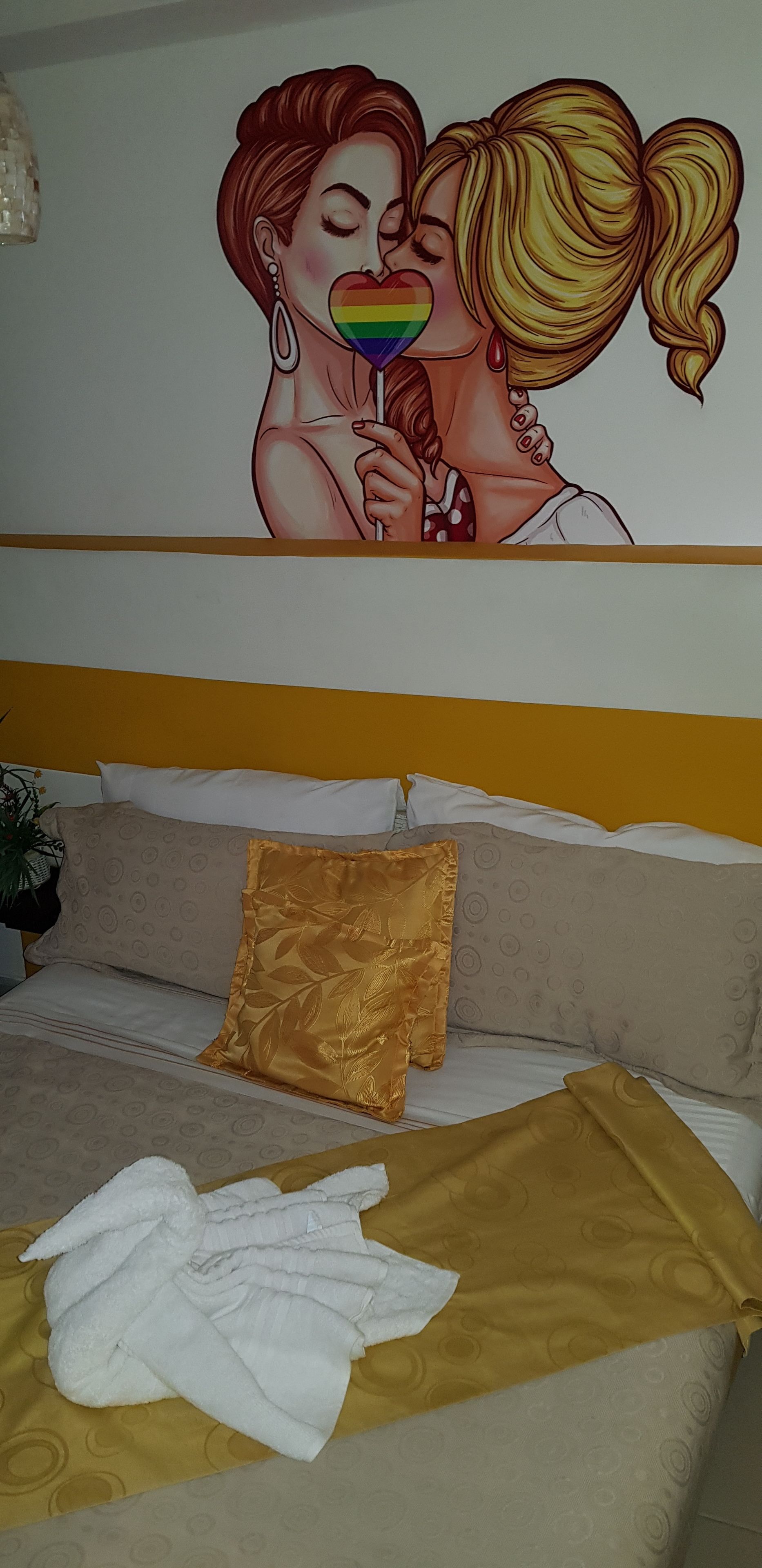 A hotel room with a bed, pillows, and a wall mural.