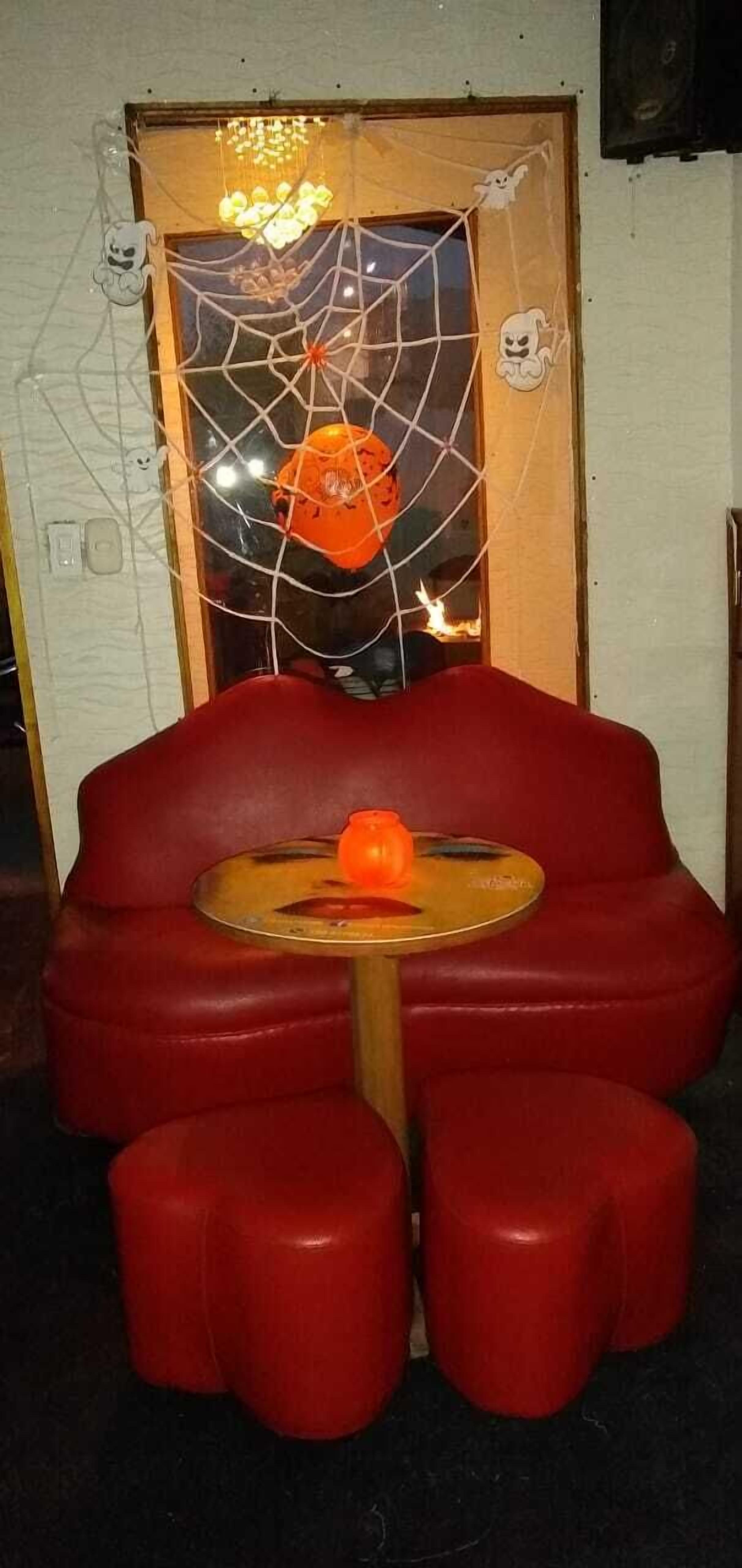 Un asiento rojo con una mesa redonda y un único objeto naranja encima.