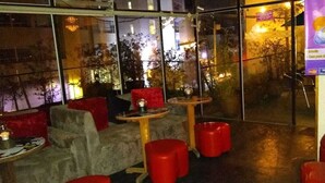 Un intérieur moderne avec des coins salon, des tables et une grande fenêtre donnant sur un paysage urbain.