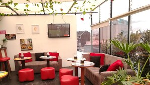 Un espace de détente moderne avec un canapé, des poufs rouges et de petites tables rondes.