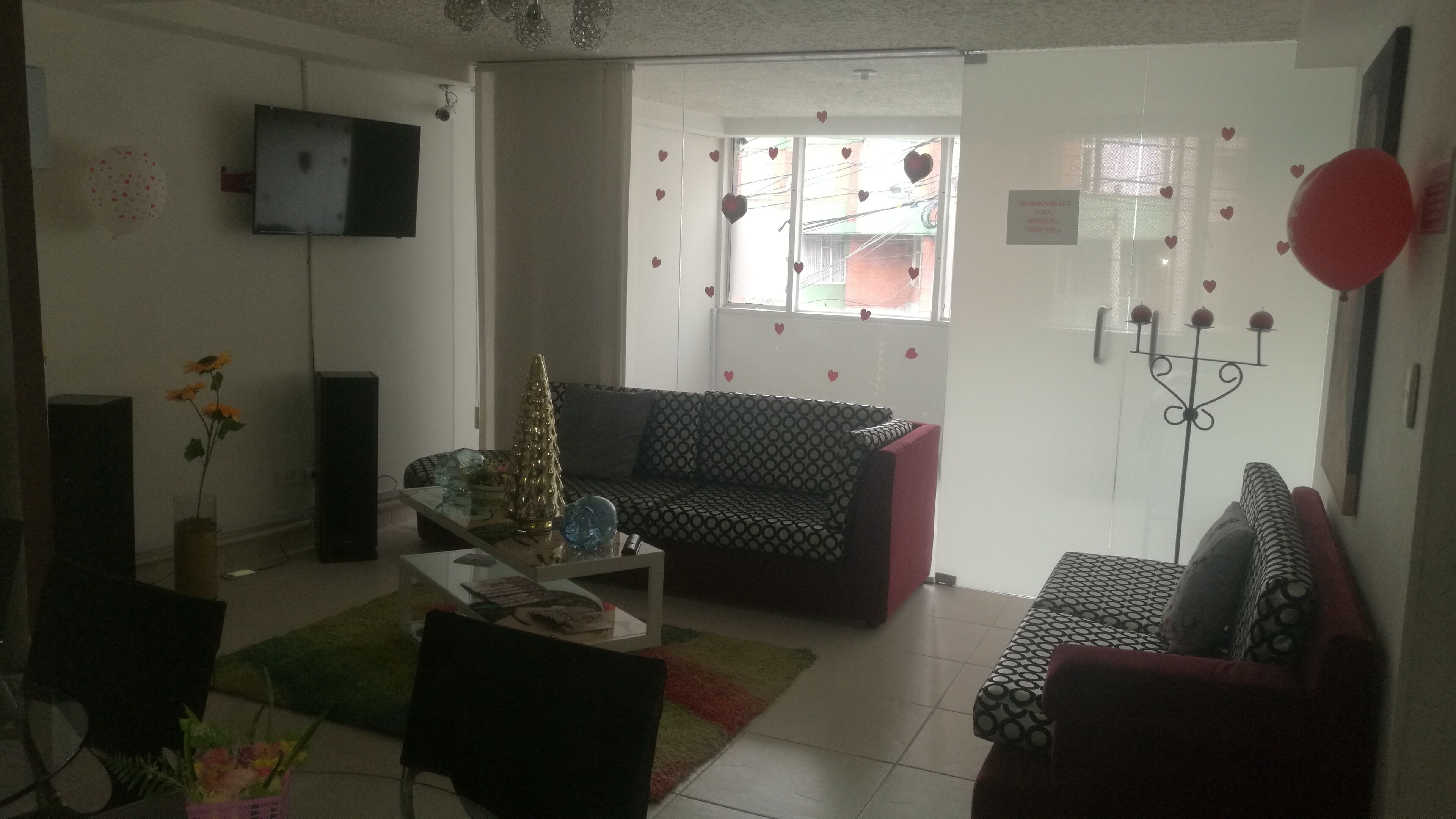 Una sala de estar con sofá, mesa de centro, televisor y un árbol decorativo navideño.