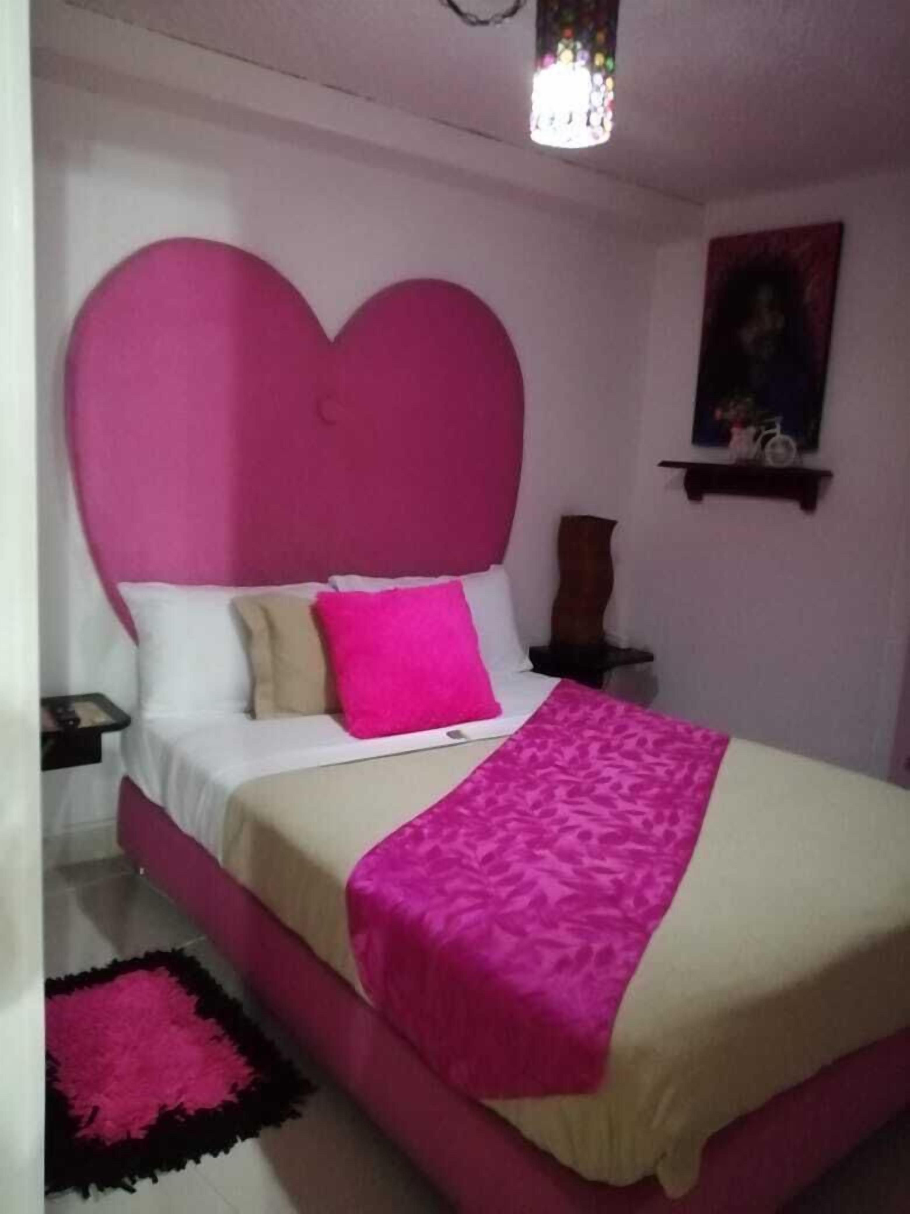 A bedroom with a bed, a nightstand, a lamp, and a painting on the wall.