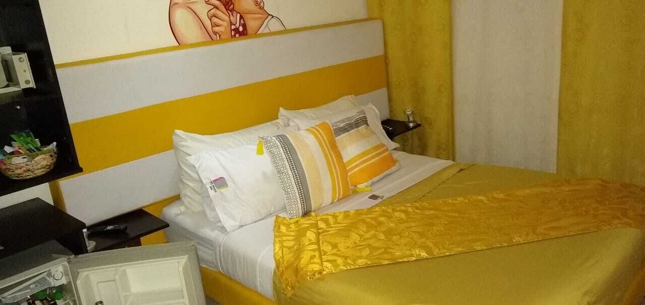 Una habitación de hotel con una cama, una mesita de noche, una lámpara y un cuadro en la pared.