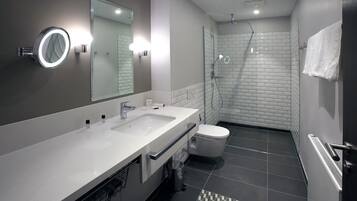 Ein modernes Badezimmer mit einem Waschbecken-Doppelplatz, Toilette, Dusche und einem Spiegel mit integrierter Beleuchtung.