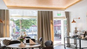 A modern cafe with a large window, a bar area with various items, and comfortable seating.
