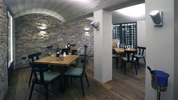 Un restaurante con paredes de piedra, mesas y sillas de madera.